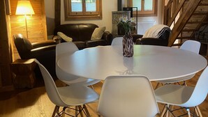 A cozy room with a round white table surrounded by white chairs, a brown leather sofa, and a wooden staircase. - Chalet Les Ravaires, Morgins (Morgins)