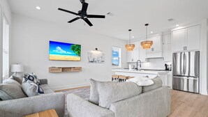 Un salon moderne avec un canapé gris, une table basse en bois et un téléviseur à écran plat.