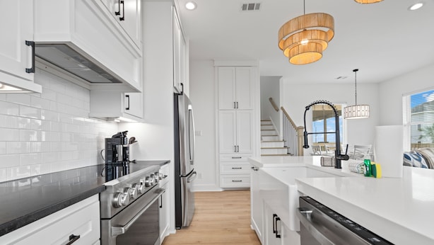 Une cuisine moderne avec des meubles blancs, des appareils en acier inoxydable et un plancher en bois.