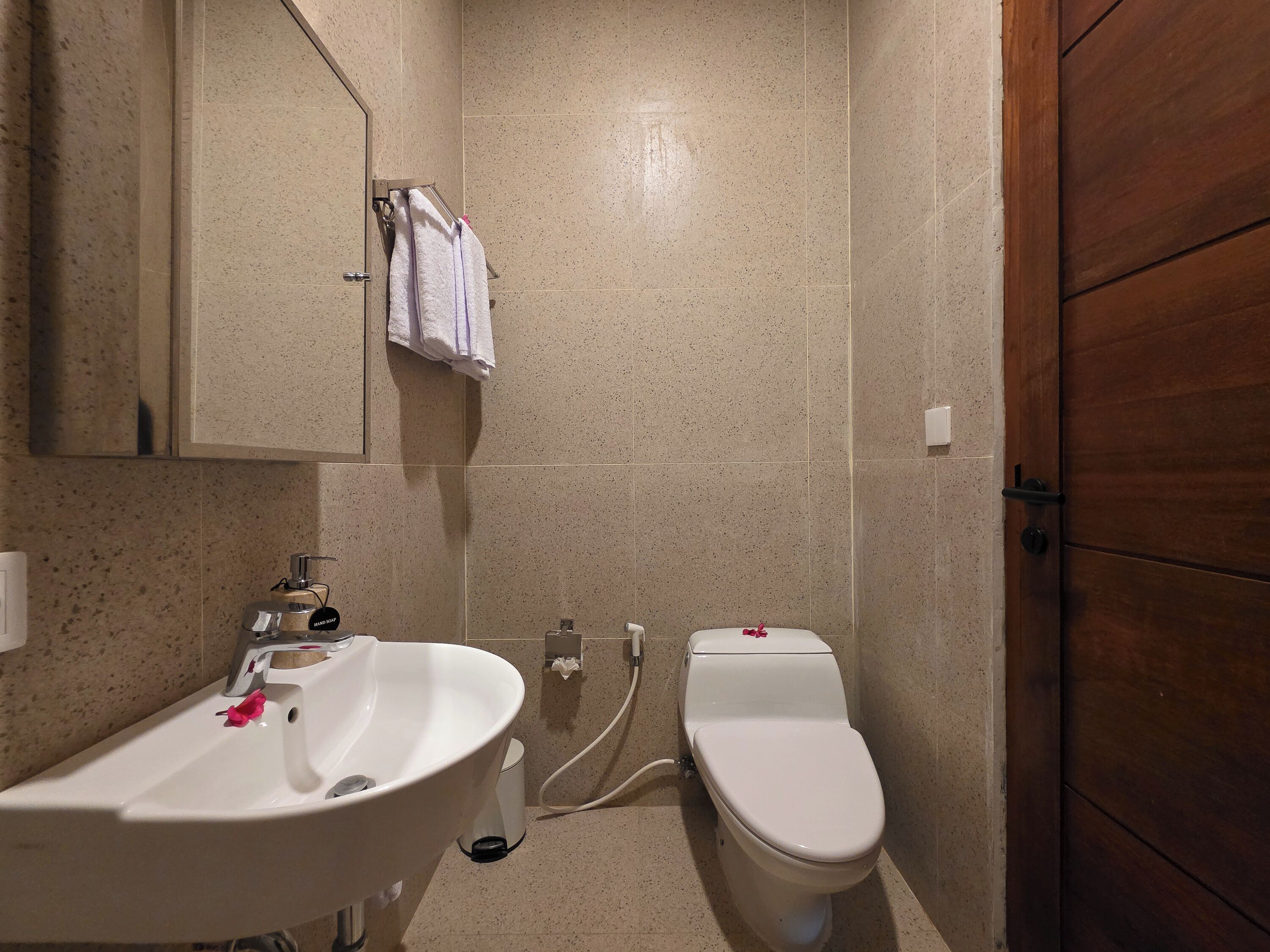 Un baño con un lavabo blanco, un inodoro y una puerta de madera.