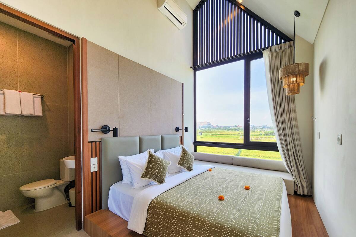 Une chambre moderne avec un grand lit, une vue sur l’extérieur et une salle de bain séparée.