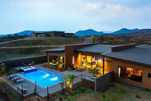 Una casa moderna con piscina, zona de estar exterior y vistas a las montañas.