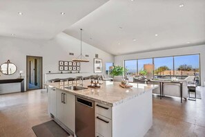 Una cocina amplia con una isla grande, electrodomésticos modernos y vistas al exterior.