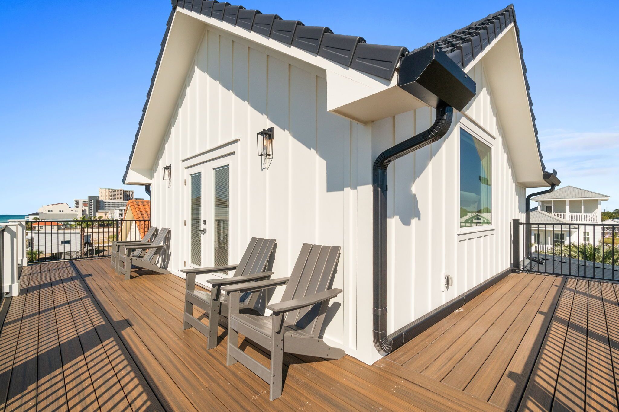 A modern building with a sloped roof and a deck with two chairs.