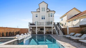 Ein großes, zweistöckiges Haus mit Swimmingpool, Gartenmöbeln und einer überdachten Terrasse.