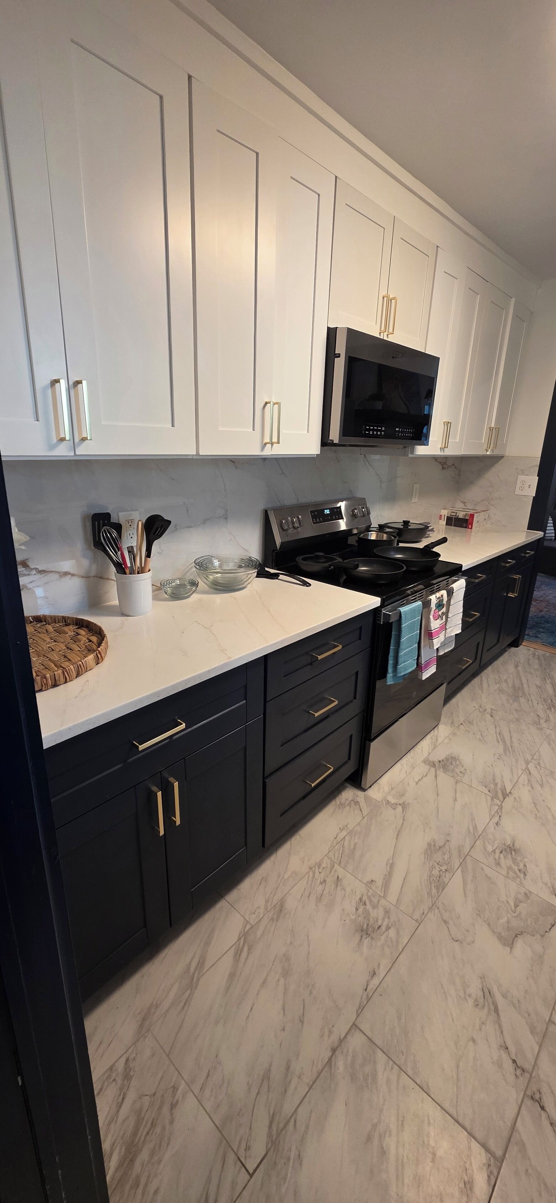 A modern kitchen with white and black cabinetry, a built-in microwave, and a stainless steel stove.