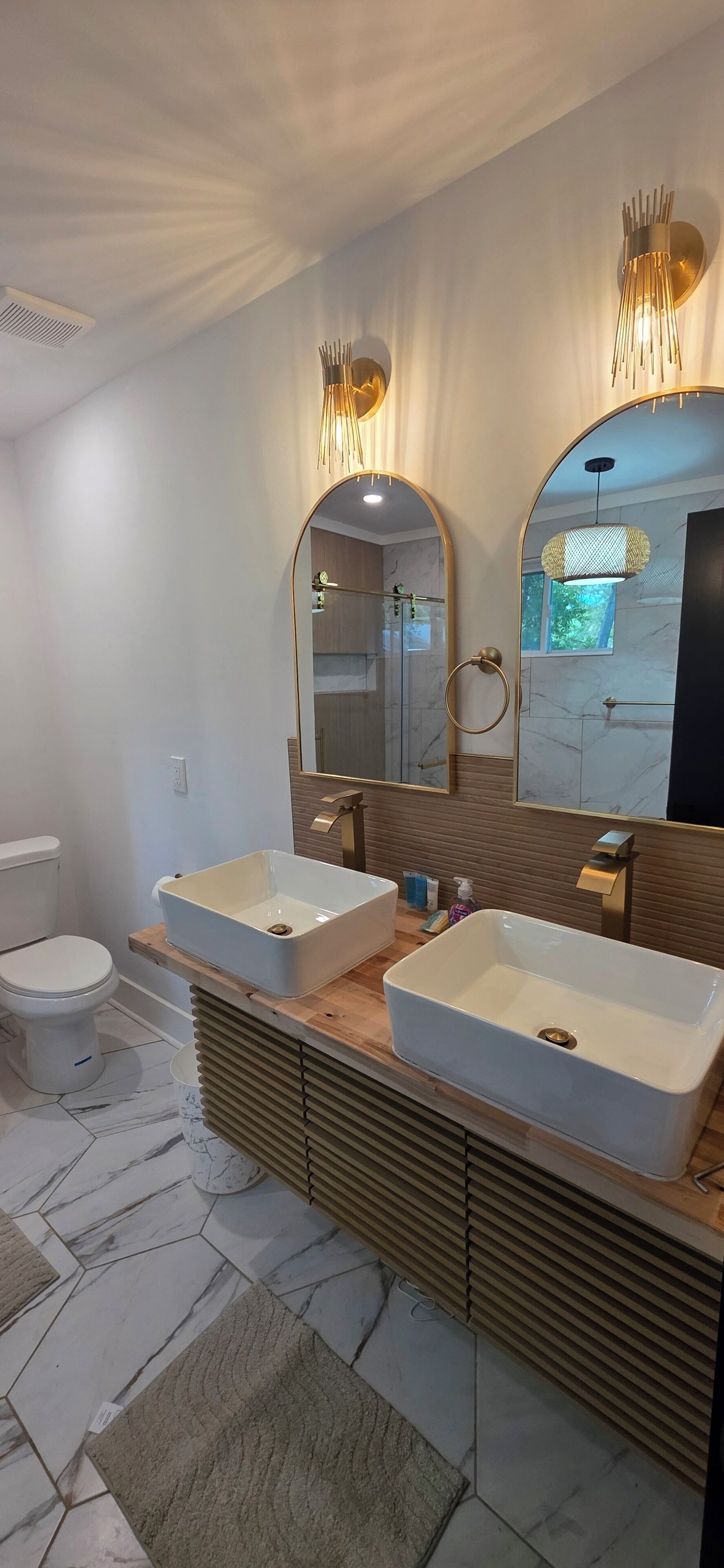 A modern bathroom with two sinks, a large mirror, and a shower.