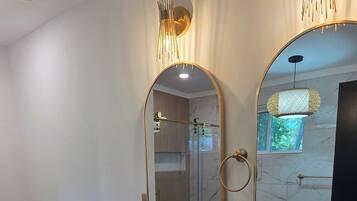 A modern bathroom with two sinks, a large mirror, and a shower.