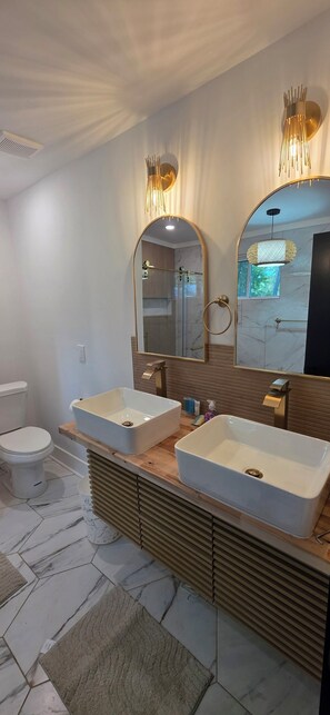 Une salle de bain moderne avec deux lavabos, un grand miroir et une douche.
