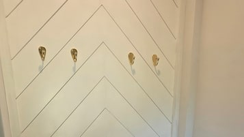 A white wall with a chevron pattern and three gold-colored hooks.