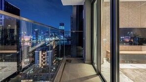 A modern balcony with a glass railing overlooking a cityscape at night. - Nice Apartments at Metropole Thu Thiem (Ho Chi Minh City)