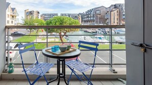 Ein Balkon mit Tisch und Stühlen, der auf einen Yachthafen mit Booten und Wohnhäusern blickt.