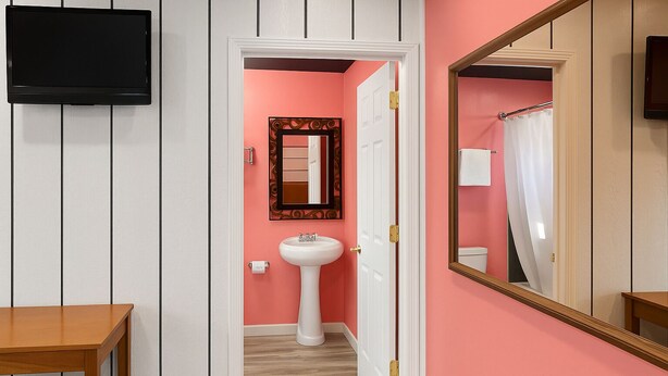 A hallway with a pink wall, a white door, a white sink, and a mirror. - Casa Valentine Inn - Los Angeles (Los Angeles)