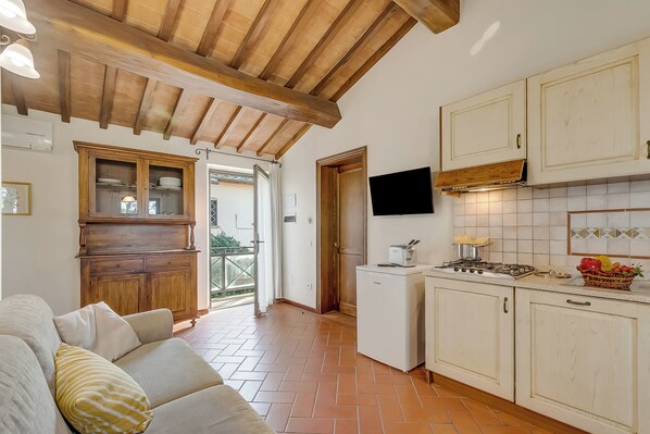 A compact kitchen with wooden cabinets, a built-in stove, and a small refrigerator.