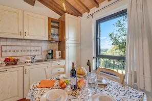 Cozinha com área de refeições e vista para o exterior, mesa posta para uma refeição.