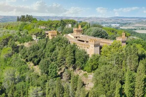 A castle surrounded by dense forest, with multiple towers and a fortified wall.