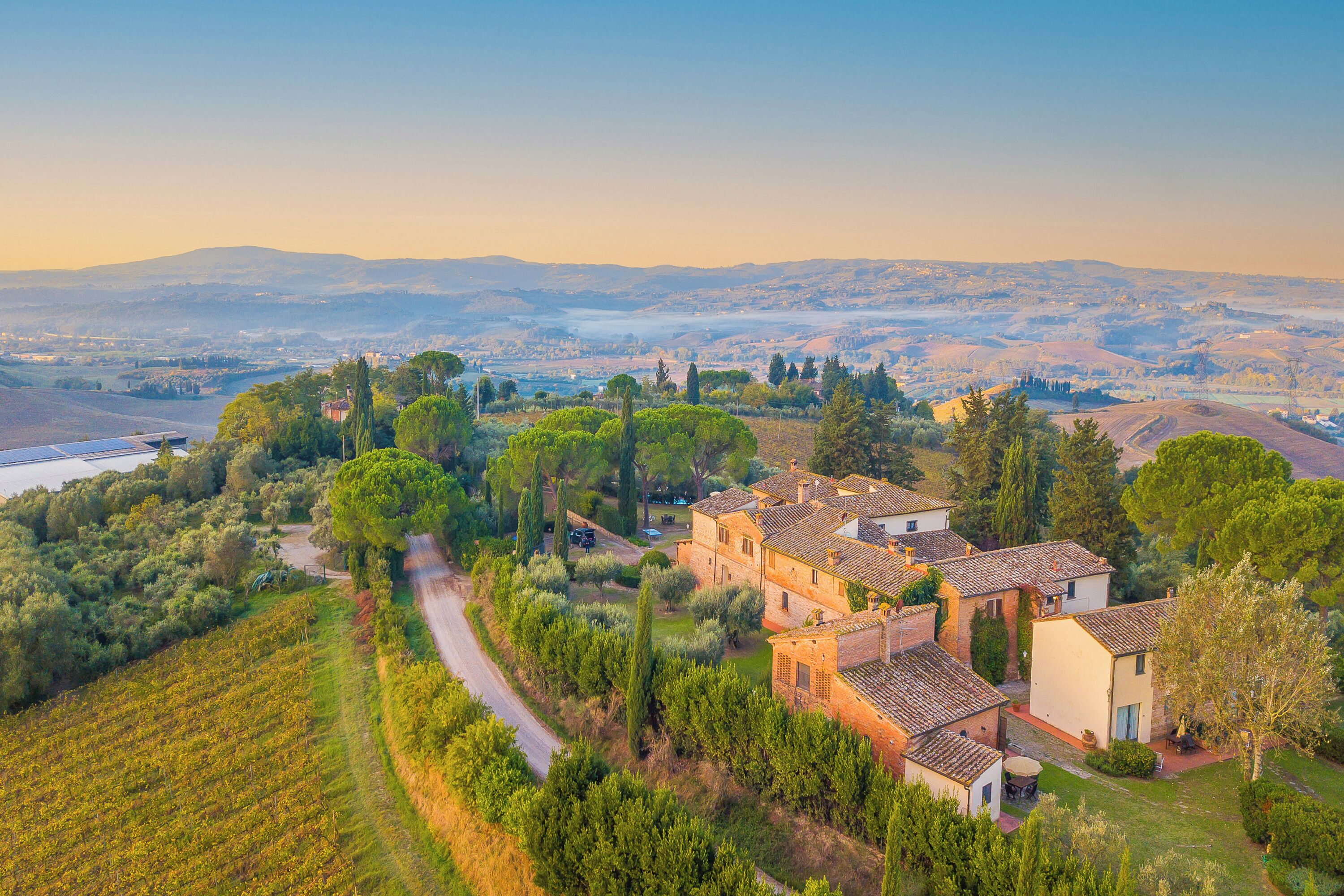 Une villa située en pleine campagne, dotée d’un vignoble, de terrasses cultivées et offrant une vue dégagée sur la campagne environnante.