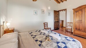Un dormitorio con cama, armario de madera y una silla.