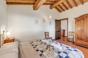 A bedroom with a bed, wooden wardrobe, and a chair.