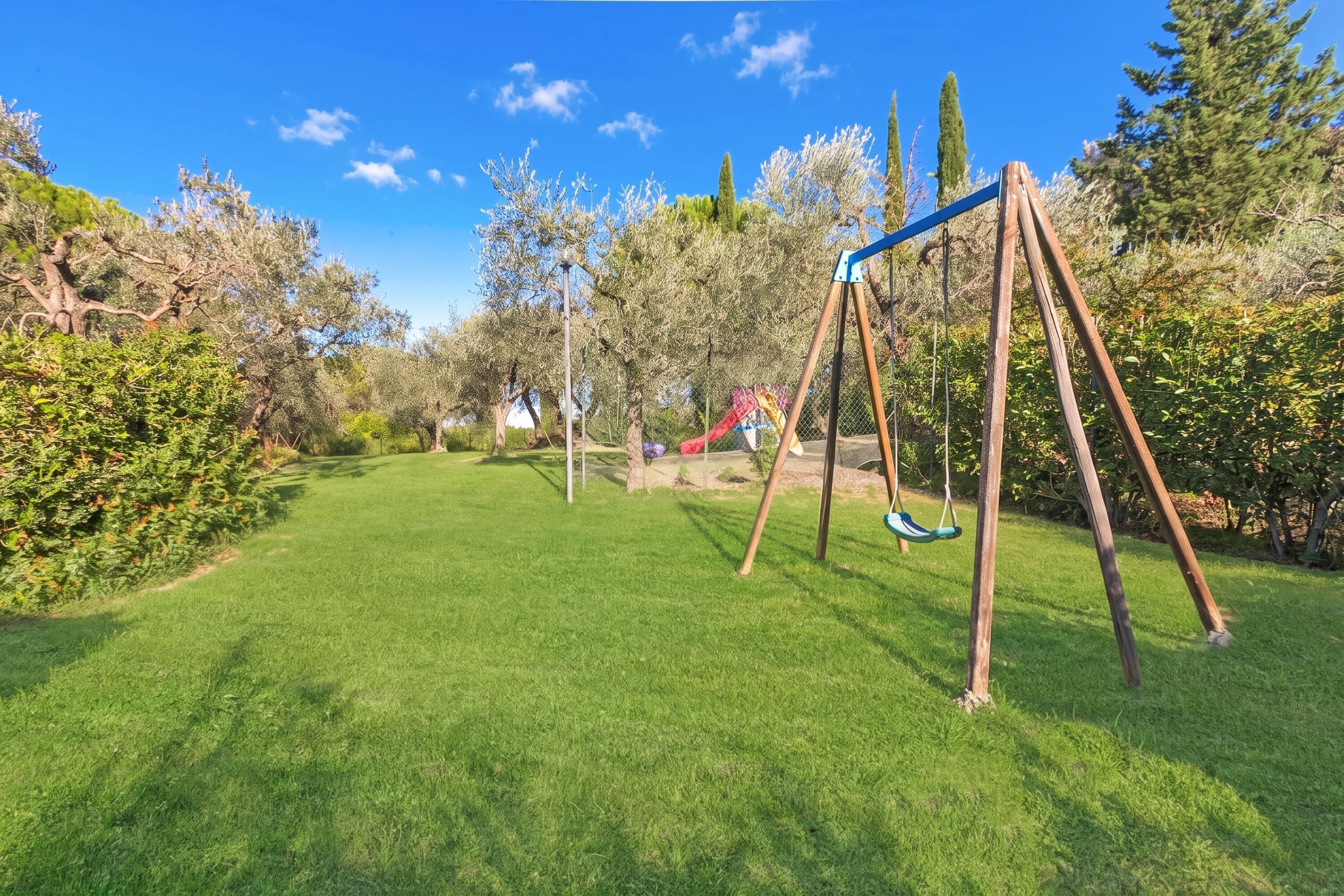 A grassy outdoor area with a swing set and a slide.