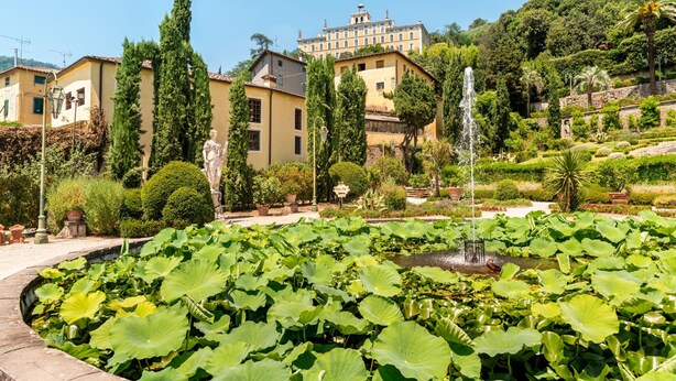 A garden with a fountain, lush greenery, and a large building in the background. - Comfortable House Private Pool & View for 6, Pescia, Italy (Pescia)