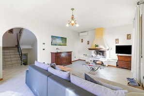 A spacious living room with a large sofa, a fireplace, and a television.