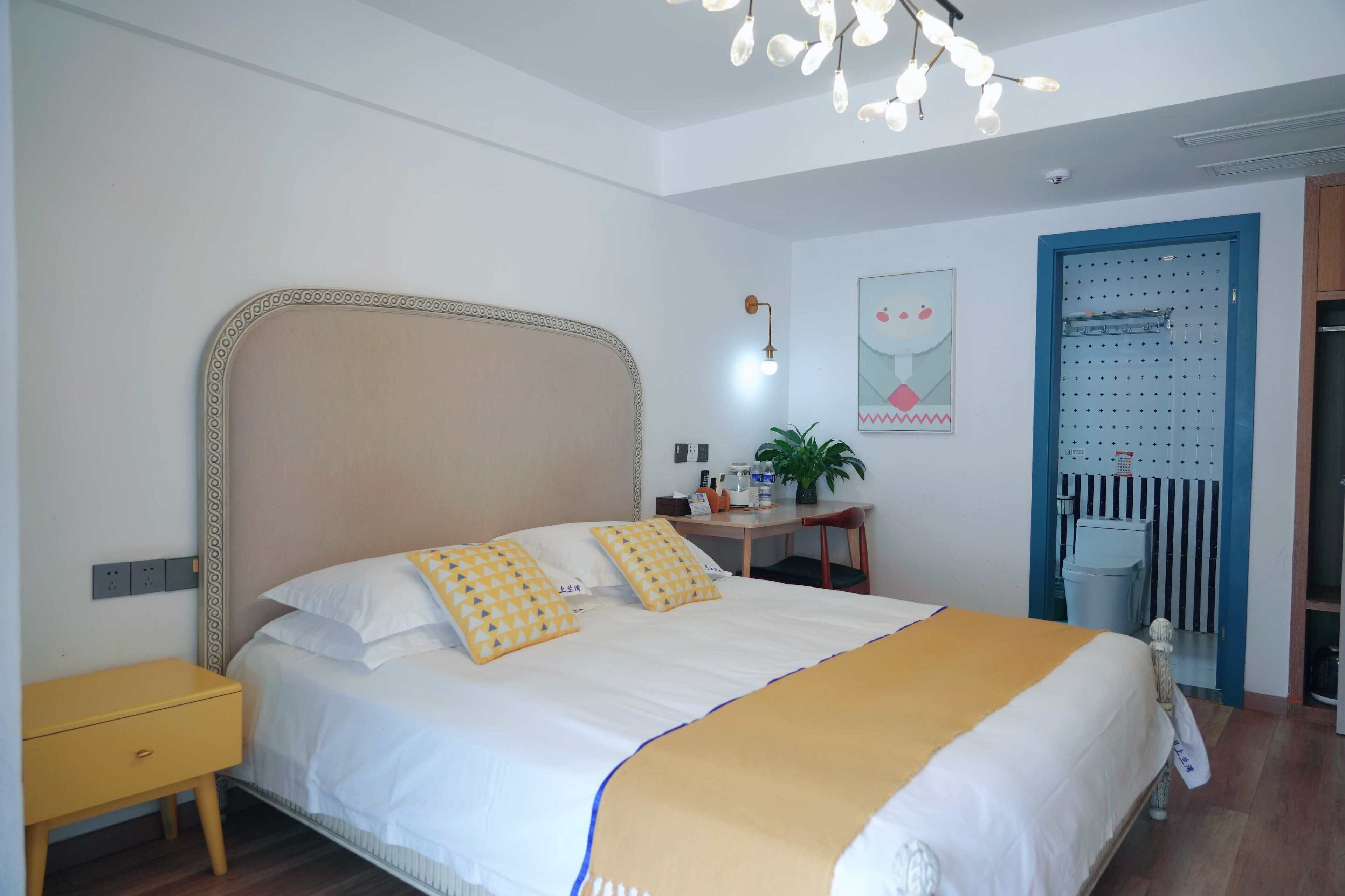 A neatly arranged bedroom with a bed, bedside table, and a desk with a chair.