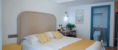 A neatly arranged bedroom with a bed, bedside table, and a desk with a chair.