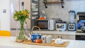 Cozinha equipada com micro-ondas, torradeira e máquina de café. Há um vaso com flores na bancada.