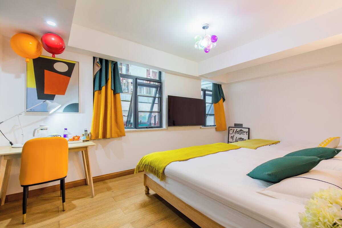 Habitación de hotel con cama, escritorio, silla, televisor y ventana con cortinas.
