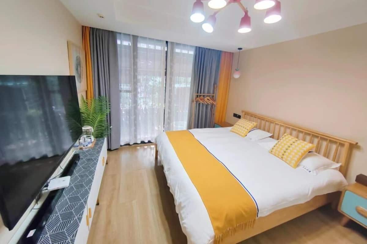 Una habitación de hotel con cama, televisión, escritorio y lámpara en el techo.