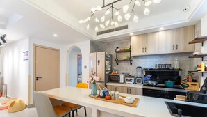 Uma cozinha moderna com armários brancos, uma ilha central com assentos e diversos eletrodomésticos, incluindo um micro-ondas e torradeira.