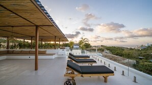 A rooftop terrace with sun loungers, a covered seating area, and a view of the sea and greenery. - Elements B2 Villa Bingin (Pecatu)