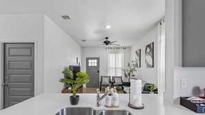 Cozinha moderna com ilha central, pias de aço inoxidável e ventoinha no teto.