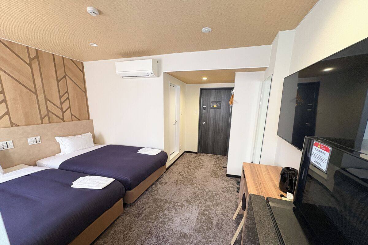 Una habitación de hotel con dos camas, televisión y escritorio.