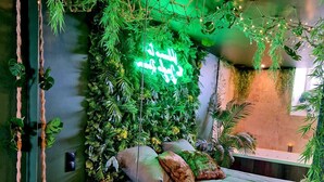 A bedroom with a bed, pillows, a bedside table, and a wall covered in green foliage. - Tropical escape Suite Jungle Room (Thiers)
