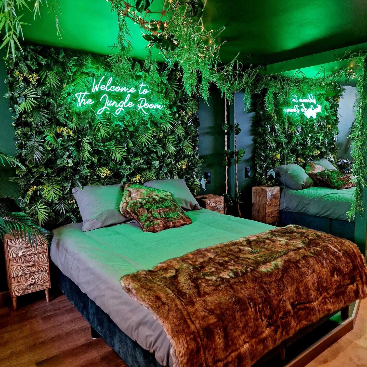A bedroom with a green-themed jungle decor, including a neon sign that reads "Welcome to the Jungle Room."