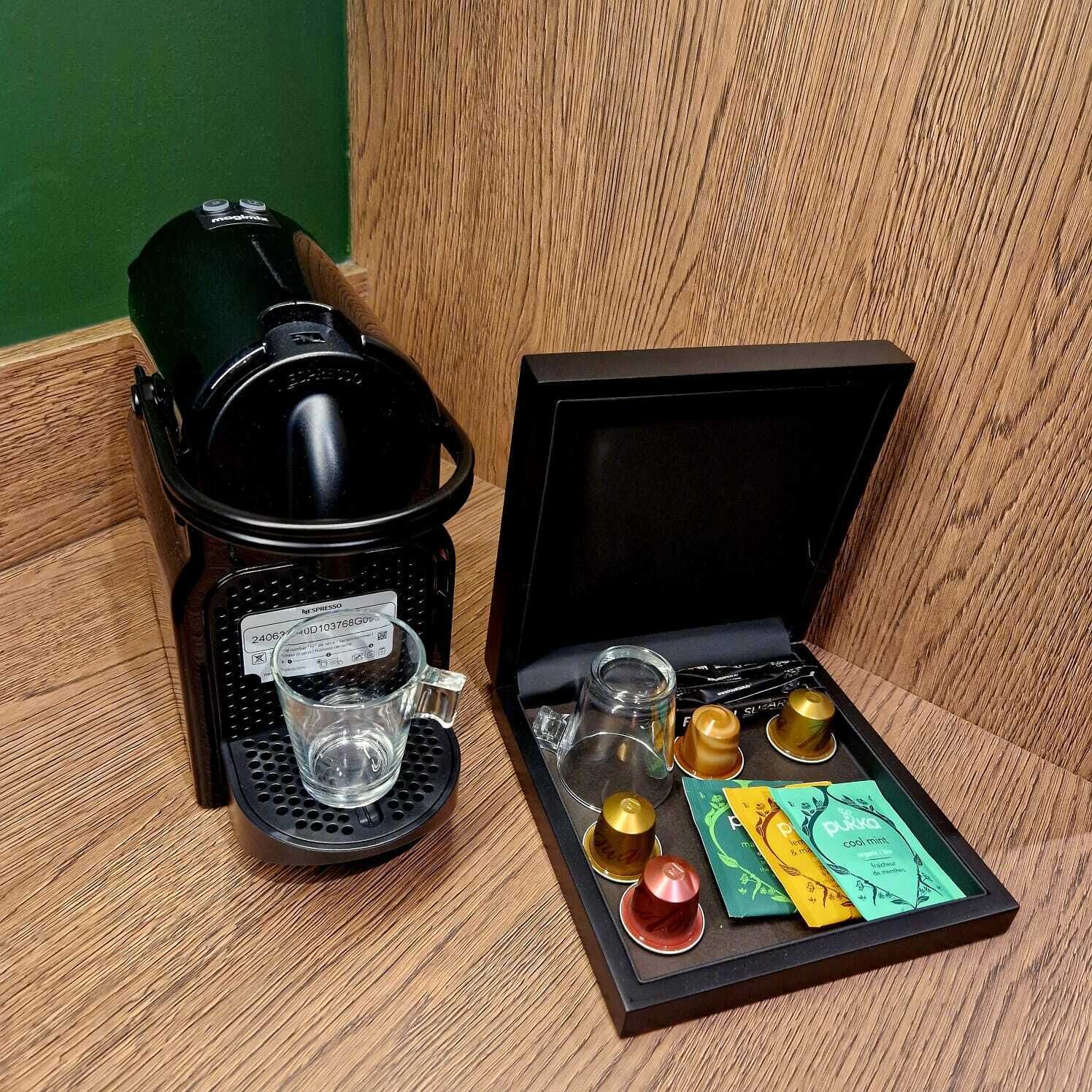 Kaffemaskine med kande af glas og kop, et sæt teskeer og teposer.