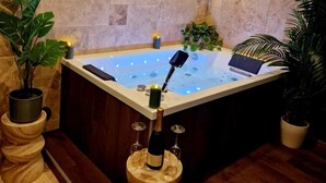 A modern bathroom with a freestanding bathtub, potted plants, and a bottle of champagne on a wooden stand. - Tropical escape Suite Jungle Room (Thiers)