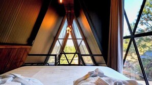 A cozy room with a bed, towels, and hanging light bulbs.