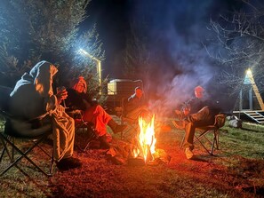 Eine Gruppe von Menschen sitzt in der Nacht am Lagerfeuer.