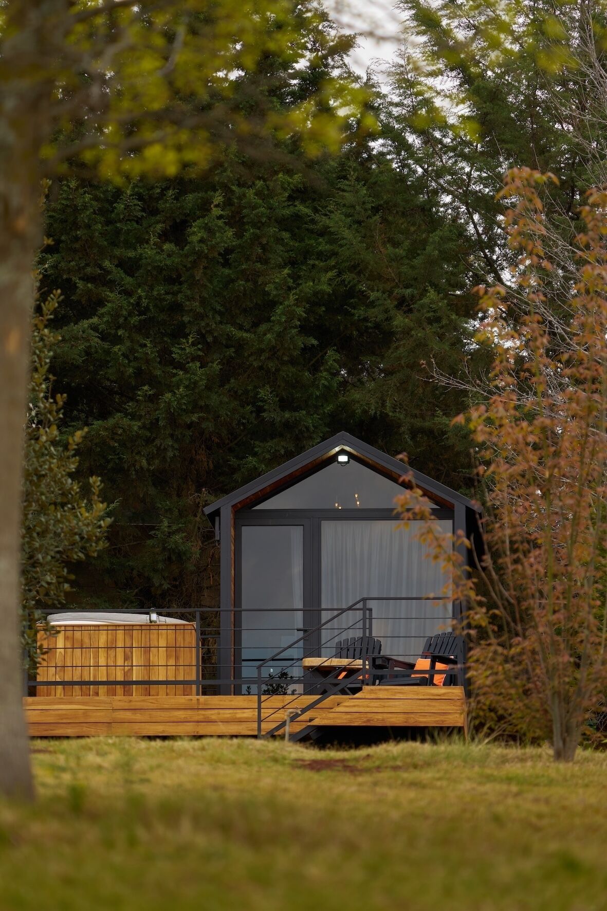 Une cabane dotée d’une terrasse en bois, d’un bain à remous et d’un espace extérieur aménagé et abrité.