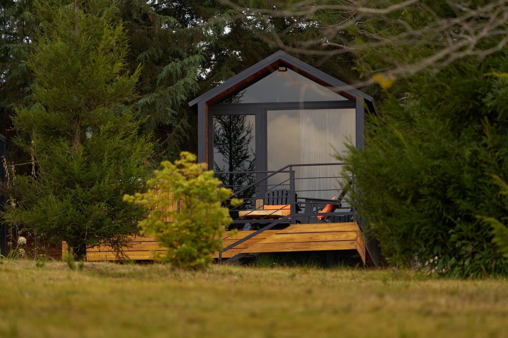 A wooden deck leading to a cabin with a sloped roof and large windows.