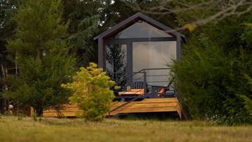 A wooden deck leading to a cabin with a sloped roof and large windows.