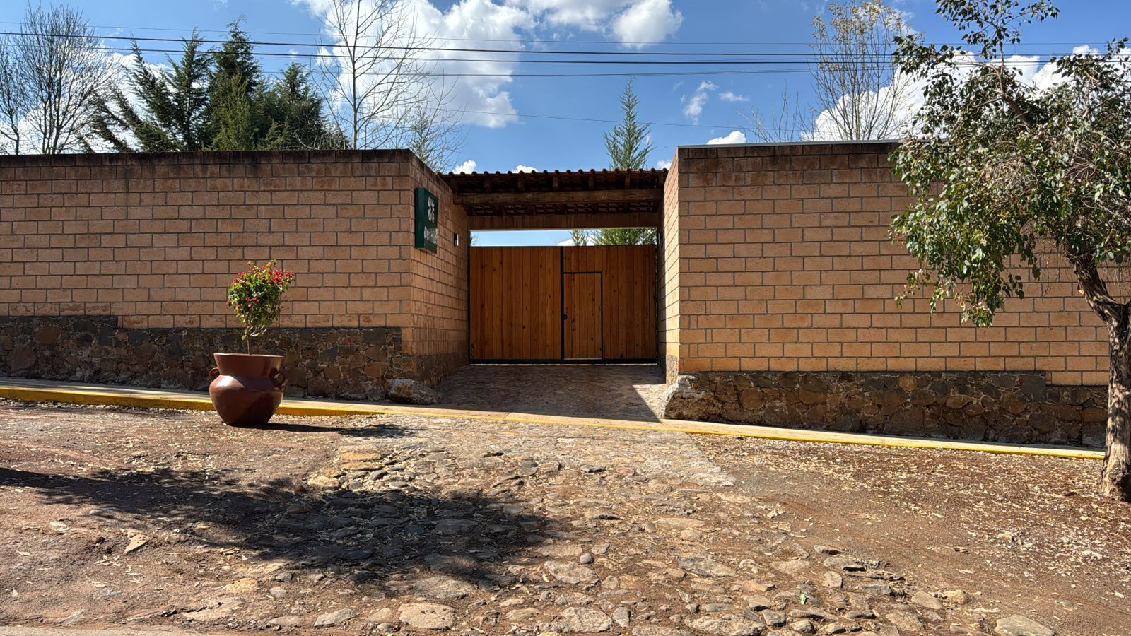 A brick building with a wooden door and a small potted plant in front.