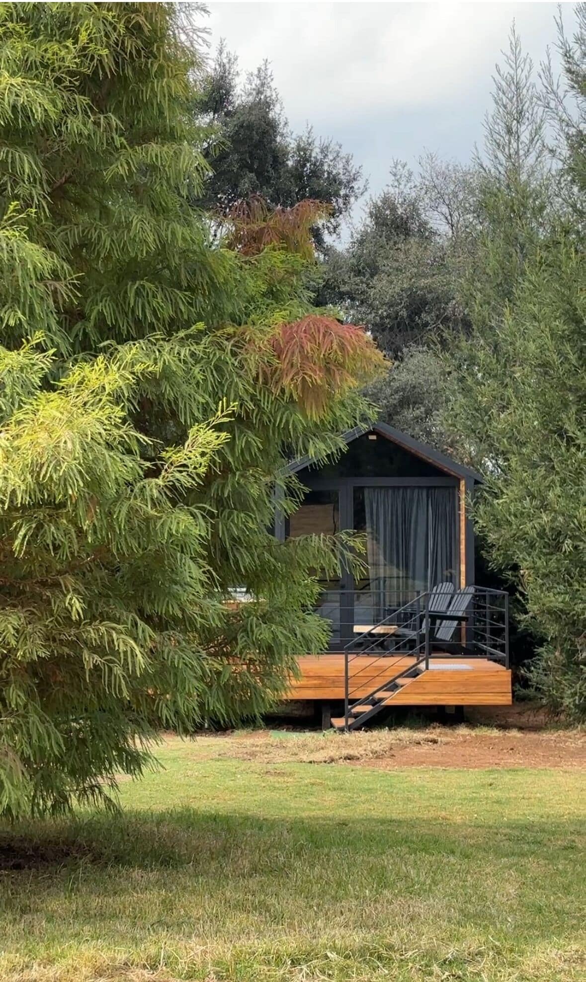 Une cabane dotée d’une terrasse en bois et d’un escalier menant à une zone abritée.