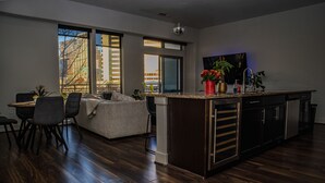 Eine moderne Küche mit einer großen Kochinsel, dunklem Holzboden und einem Essbereich mit einer Couch und Stühlen.