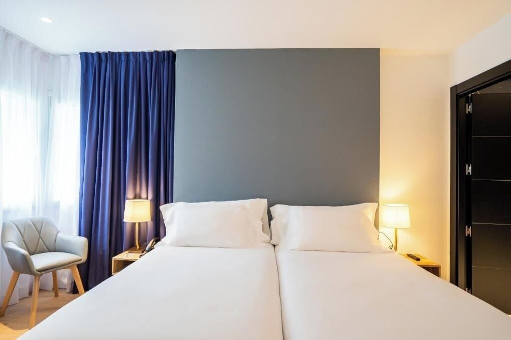 Recharge in a serene twin room framed by soft curtains.
