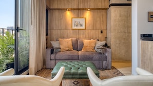 A modern living room with a grey sofa, two cushions, a green ottoman, and a framed picture on the wall. - Rooftop - in Roma Norte (Mexico City)