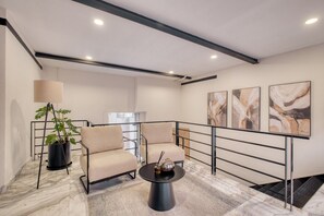 A modern hotel room with a marble floor, two beige armchairs, a coffee table, a floor lamp, and abstract wall art. - Rooftop - in Roma Norte (Mexico City)